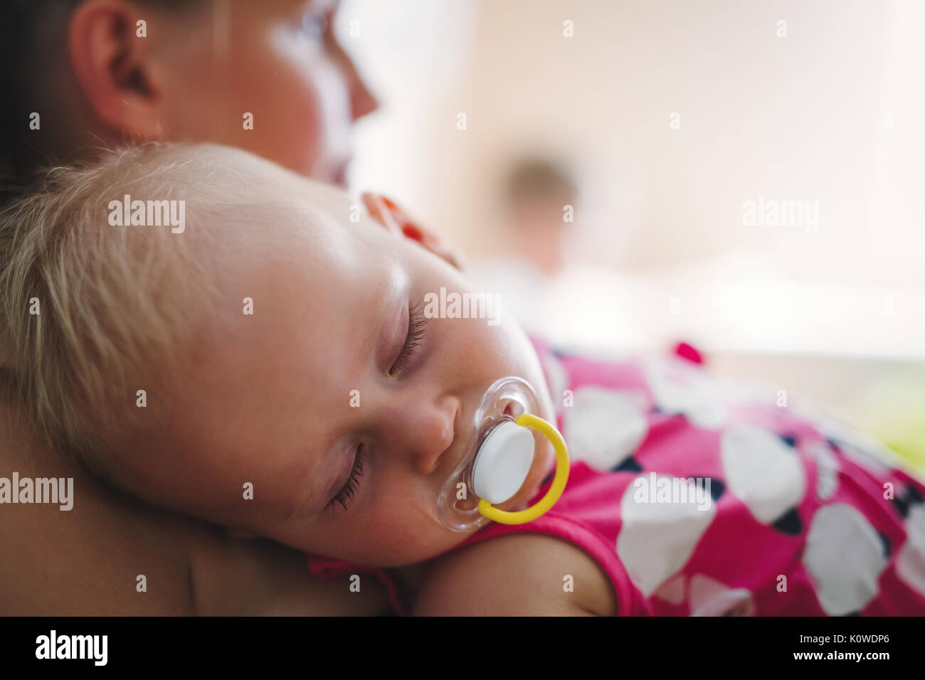 Junge Mutter hält ihr schlafendes Neugeborenes Stockfoto