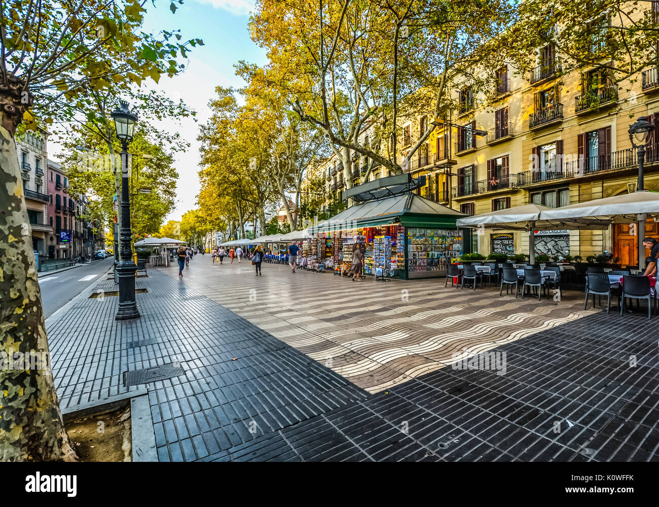 Morgen auf La Rambla in Barcelona, Spanien, bevor die Touristen kommen als Cafe macht sich bereit für Business und eine Frau kauft Souvenirs aus einem Ständer Stockfoto