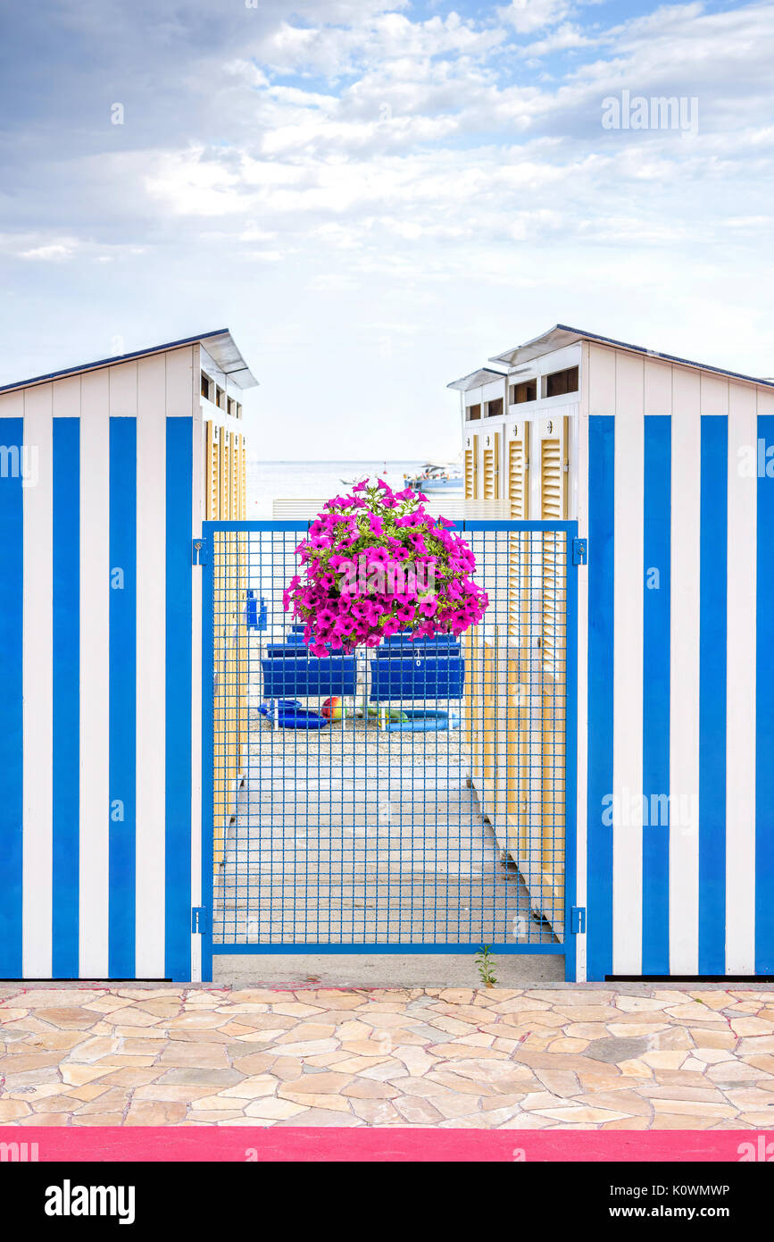 Blaue streifen Umkleidekabinen und lila Blumen am Strand von Santa Margherita Ligure, Italien Stockfoto