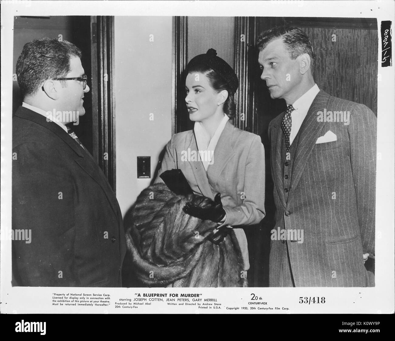 Ein Film noch Szene aus "eine Blaupause für Mord" (1953 Twentieth Century Fox thriller), eine elegante Frau Ernst im Gespräch mit einem Mann mit Brille und einem dunklen Anzug, während der andere Mann hinter sich aufmerksam zuhört, 1953. Stockfoto