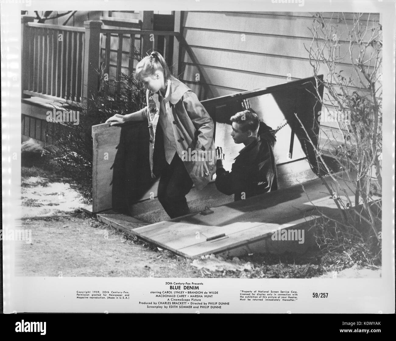Ein Film noch Szene aus 'Blue Jeans' (1959 Twentieth Century Fox Film), in dem Sie zwei Jugendliche, ein Junge und ein Mädchen, Klettern aus einem Sturm Keller, mit dem Mädchen ausgehen, wie der Junge hinter die Klappe offen hält, 1959. Stockfoto