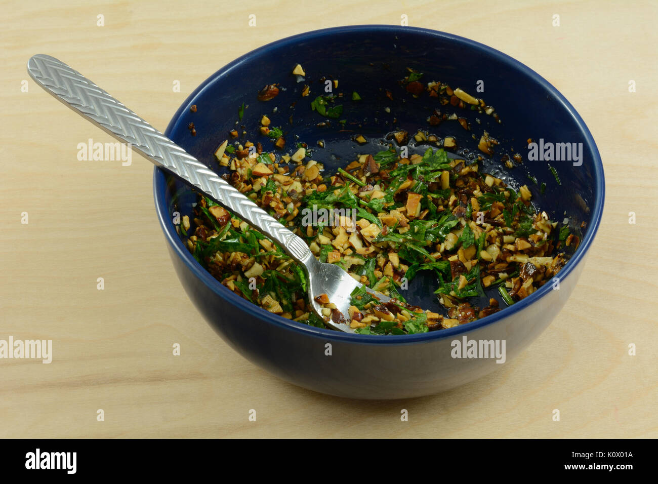 Die gremolata Sauce mit gehackten Mandeln, Petersilie und Knoblauch in blaue Schale mit Gabel Stockfoto