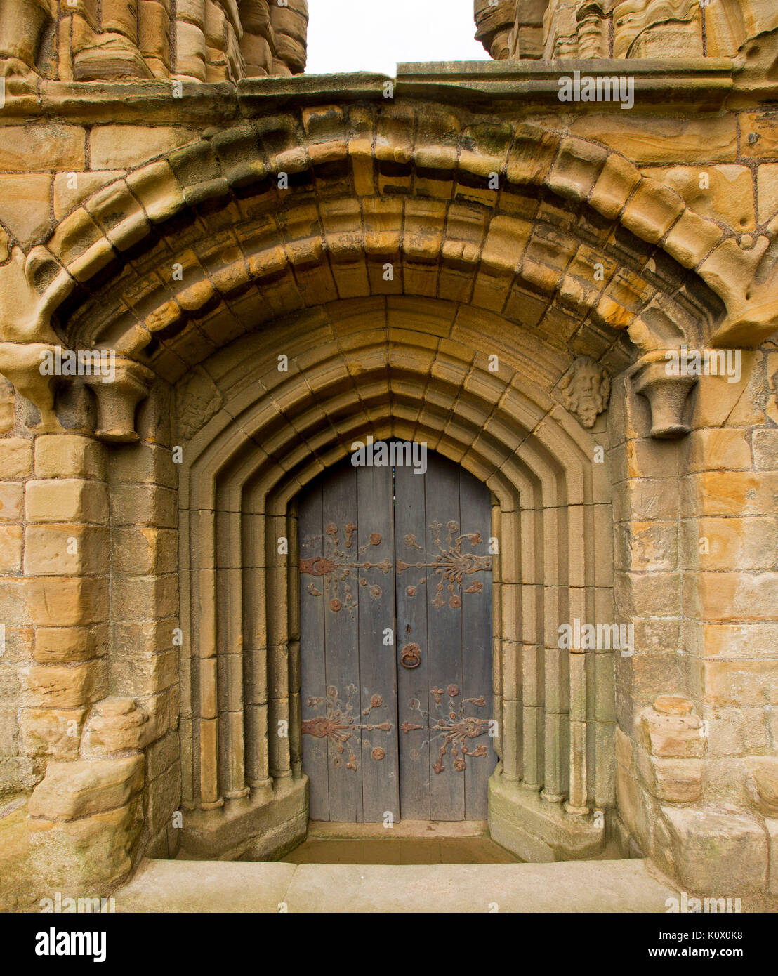 Gewölbten Tür mit verzierten Scharniere durch eine Reihe von dekorativen Steinbögen an historischen Tynemouth priory Ruinen umgeben, England Stockfoto