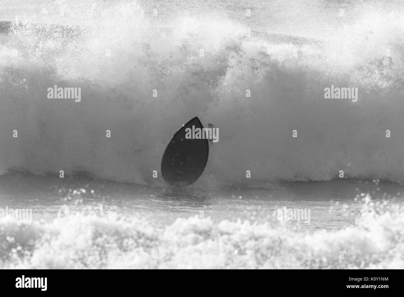 Surfer Surfen Absturz verlässt Vorstand und Ocean Wave dramatische schwarz-weiß Foto. Stockfoto