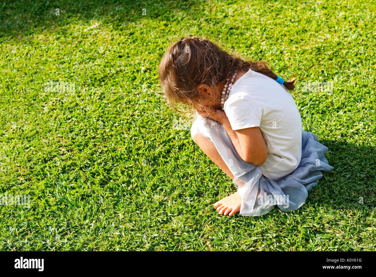 Ein junges Mädchen in einem Wutanfall und weinend auf dem Rasen Stockfoto