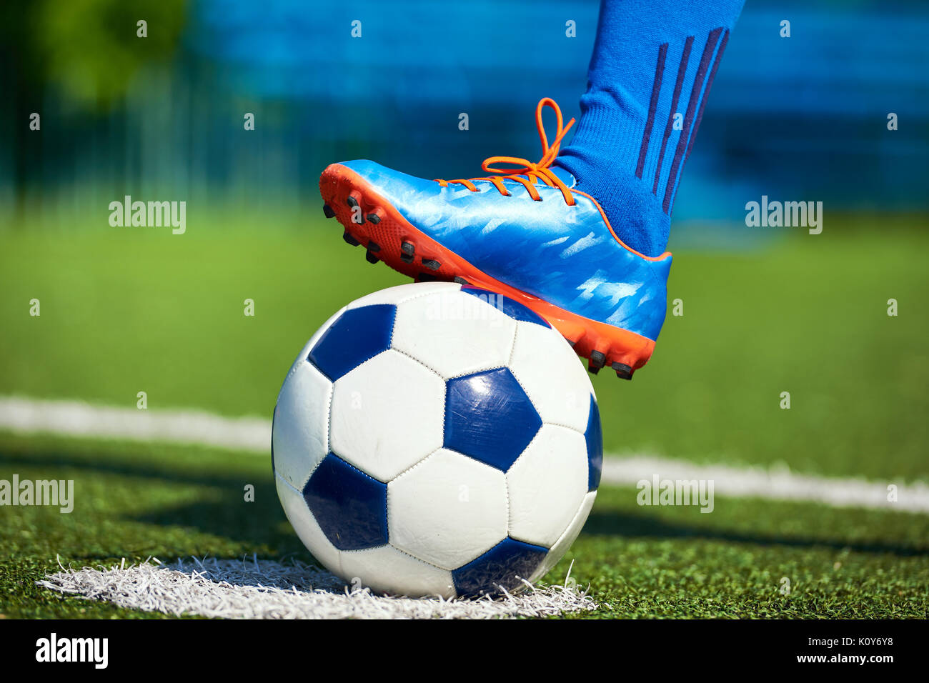 Fuß eines Fußball-Spieler in einem Fußballschuh, der auf einer Kugel auf einer künstlichen grünen Rasen des Stadions Stockfoto