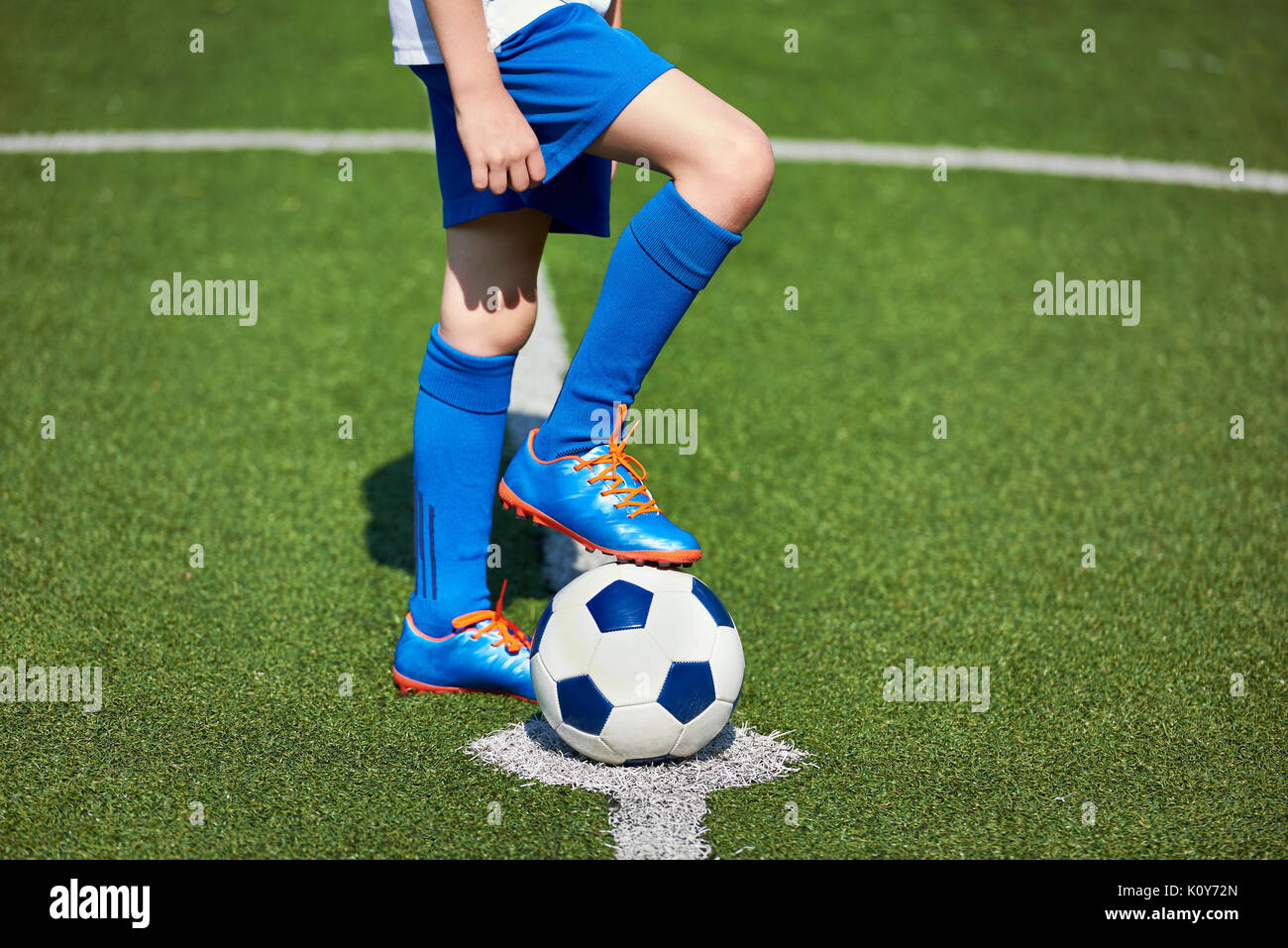 Fuß eines Fußball-Spieler in einem Fußballschuh, der auf einer Kugel auf einer künstlichen grünen Rasen des Stadions Stockfoto