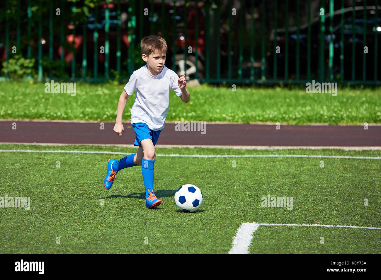 Junge Fußball-Spieler läuft mit dem Ball auf dem grünen Rasen des stadiumм Stockfoto