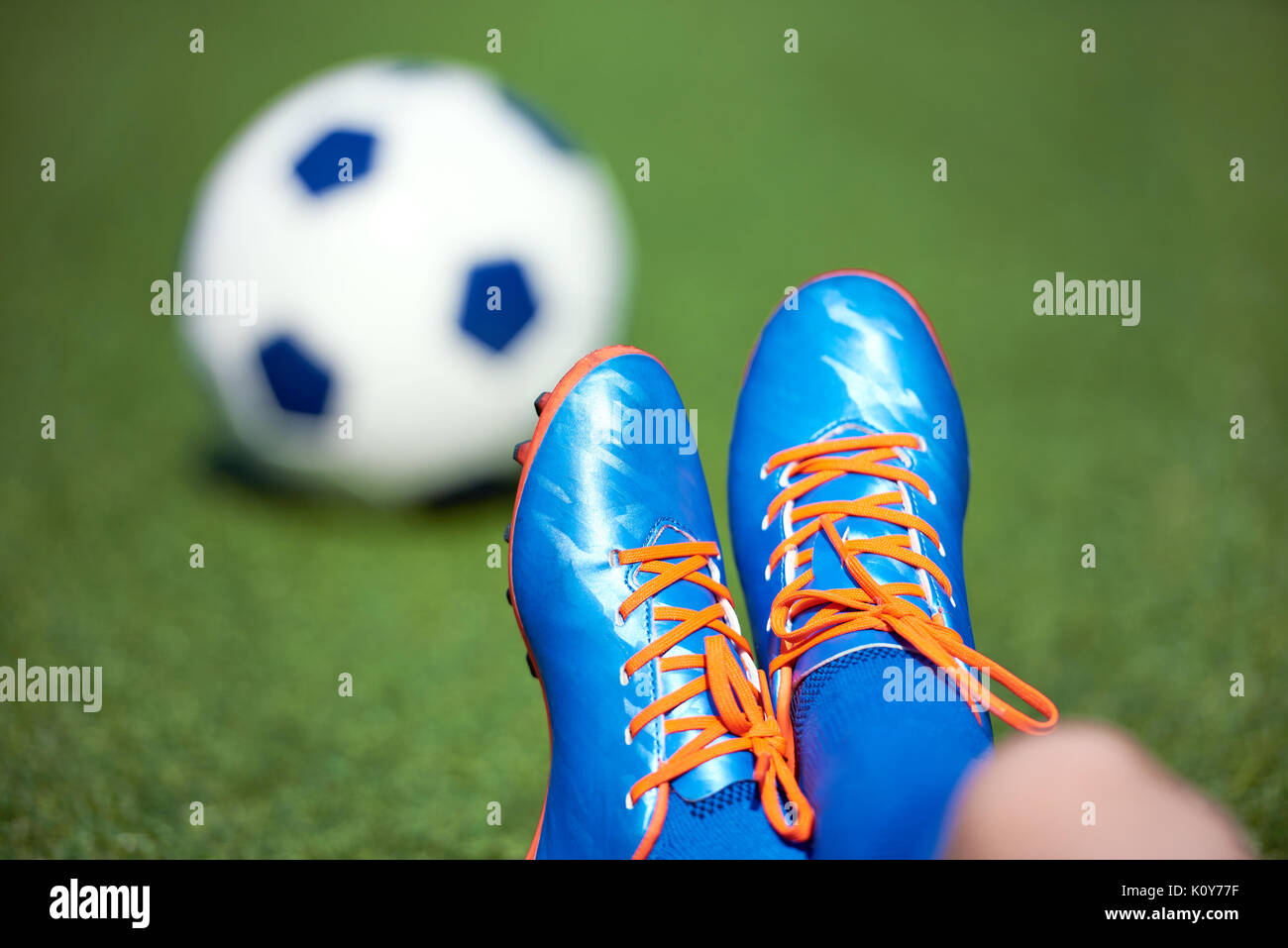 Fußballschuhe für junge Fußballspieler mit Ball auf Gras Stockfoto