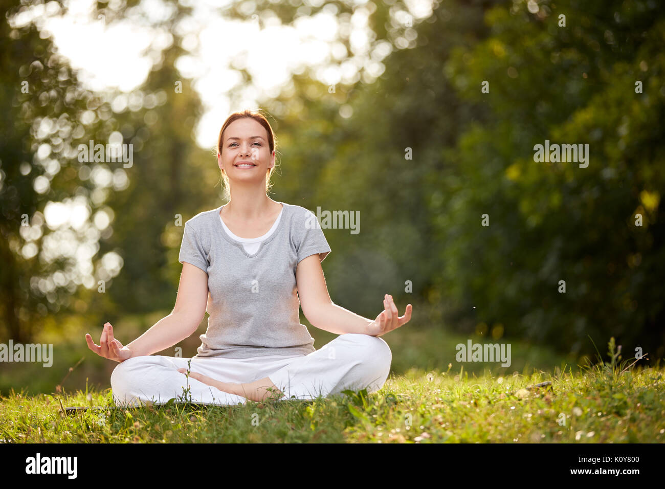 Weibliche Person im Yoga pose im sonnigen Natur Stockfoto
