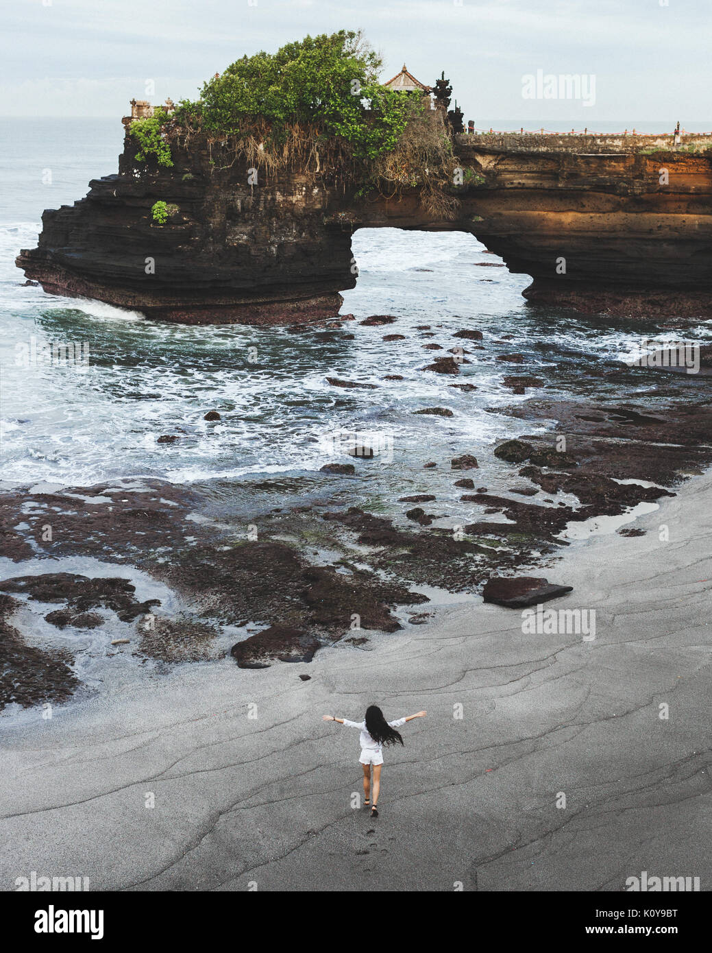 Glückliche Frau durch leere Batu Bolong Beach in der Nähe von Heiligen balinesischen Tempel Tanah Lot läuft. Niemand um am Morgen. Freiheit und Freude. Heilige pura für loc Stockfoto