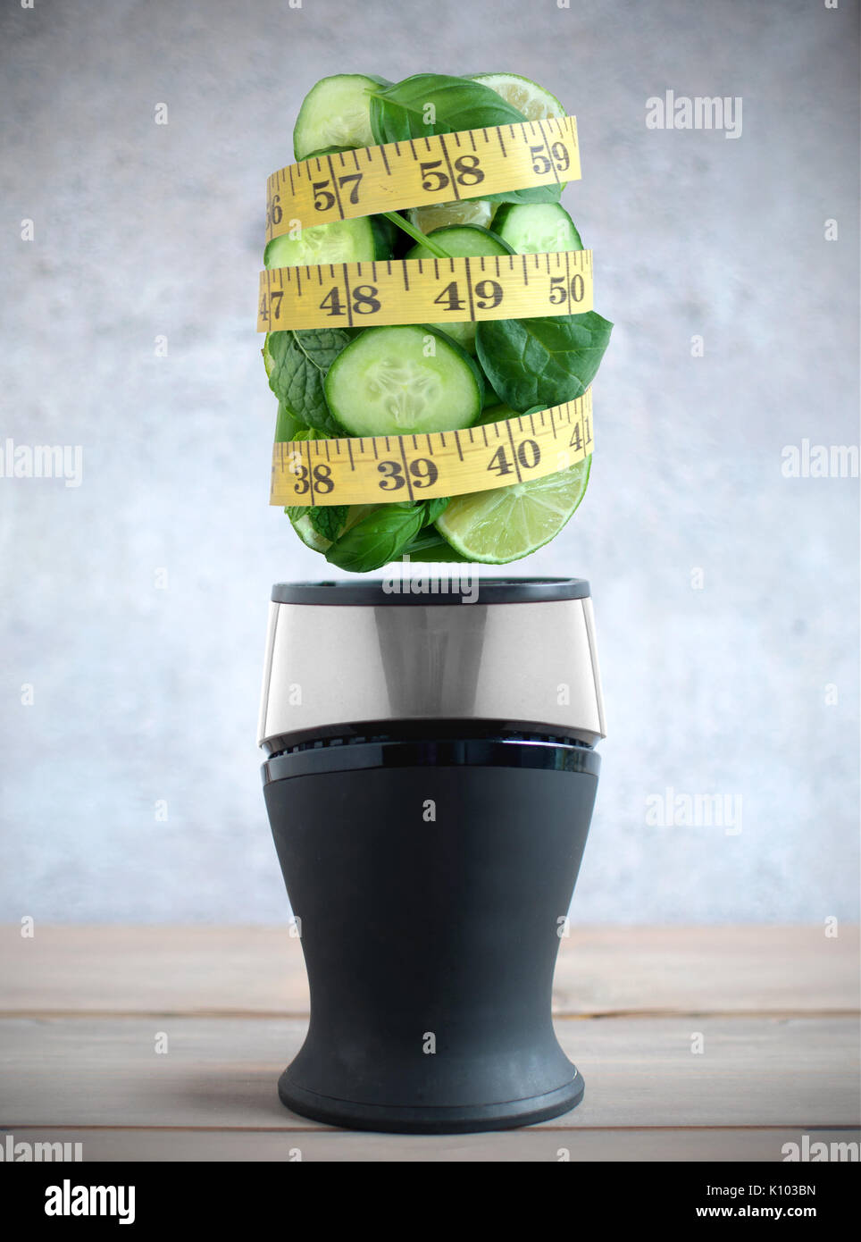 Maßband um frische grüne Früchte und Gemüse Zutaten schweben über einen Mixer Stockfoto