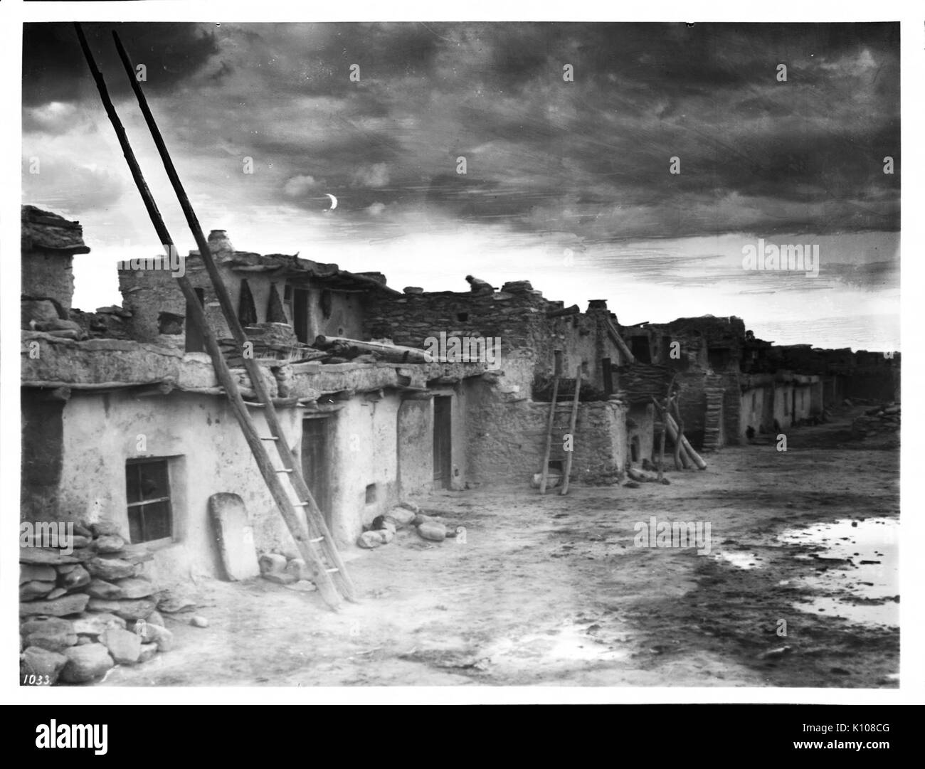 Dieses Foto aus der Zeit um 1900 zeigt lehmziegelwohnungen in Shonguapavi, einem Dorf der Hopi. Das Bild fängt die traditionelle Architektur und die nächtliche Atmosphäre dieser indianischen Gemeinde ein. Stockfoto