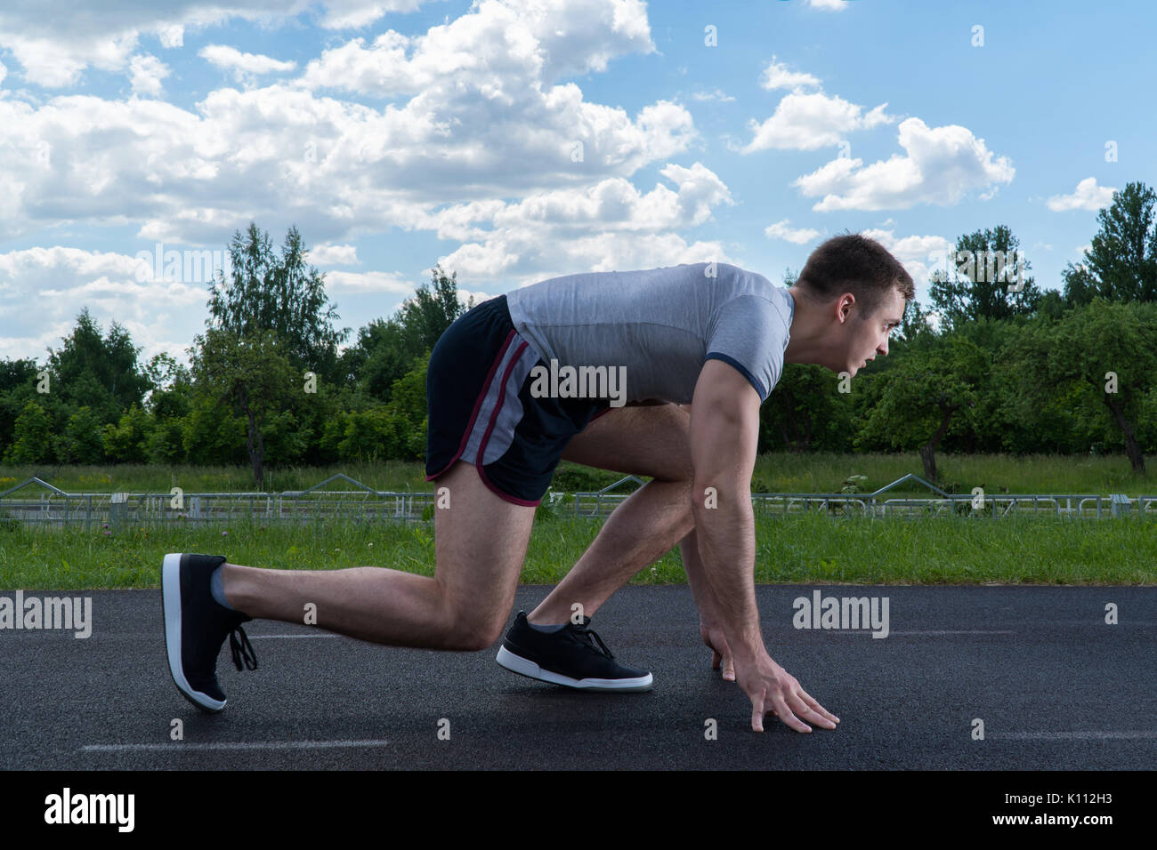 Der Mann läuft rund um das Stadion. Training im Freien. Von der Seite sehen. Stockfoto