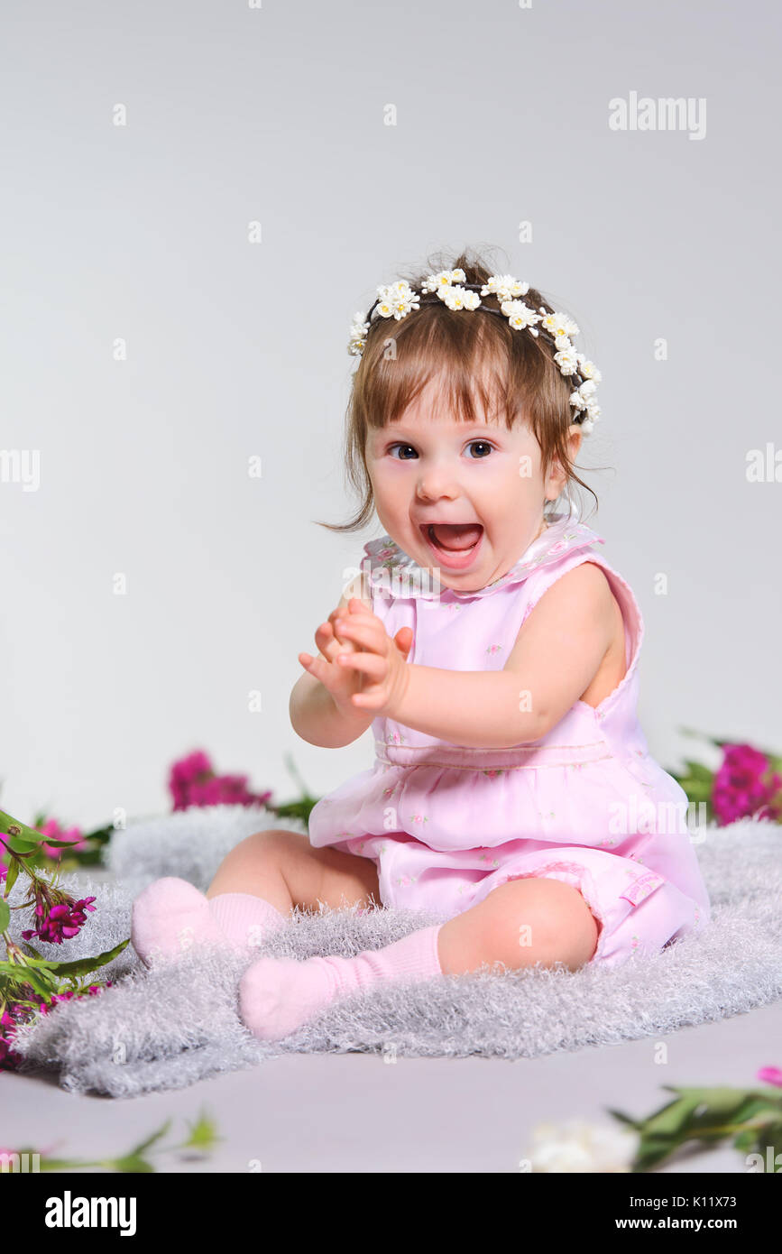 Glückliches Kind lachen mit einer Blume auf grauem Hintergrund Stockfoto