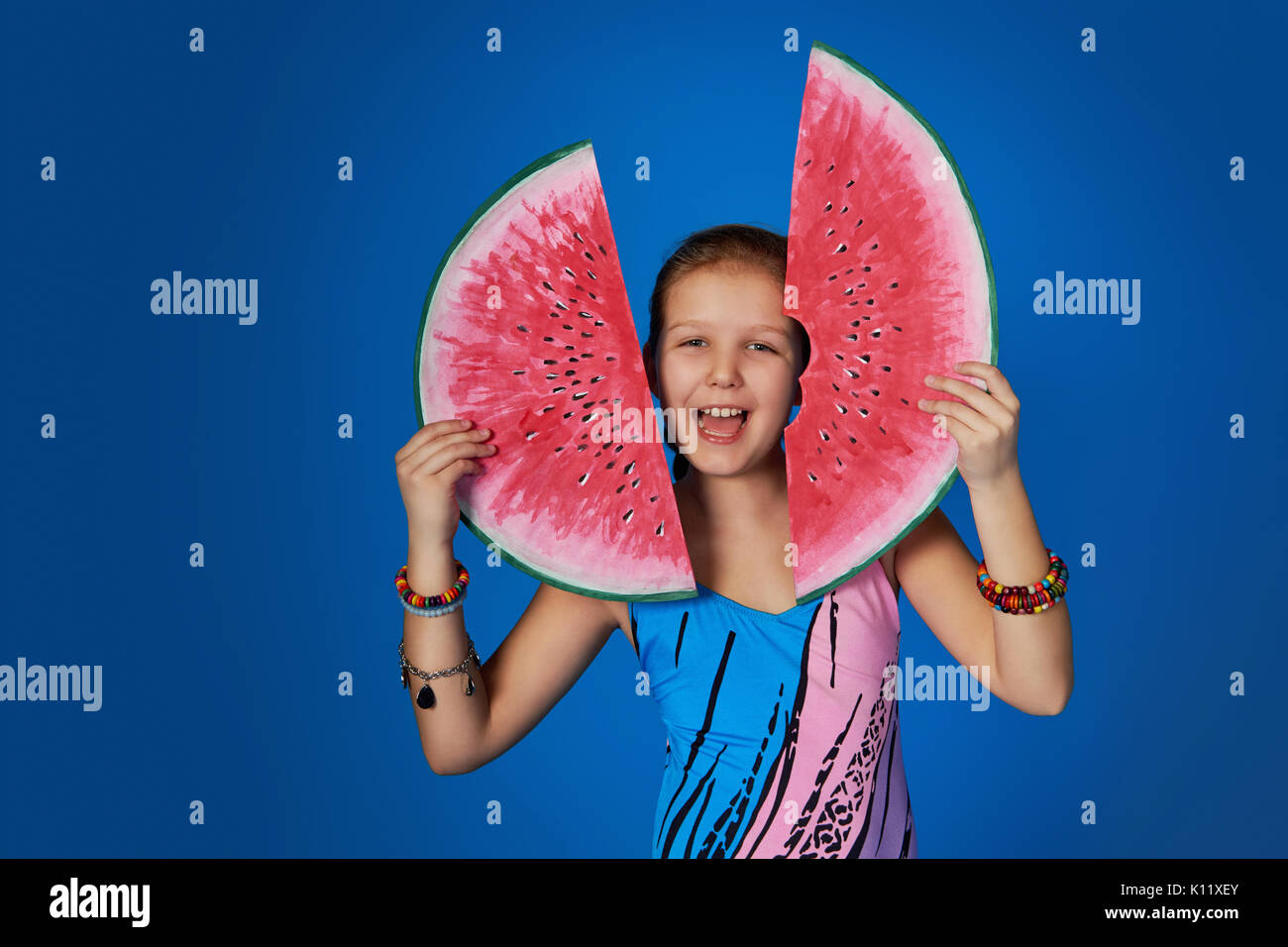 Portrait von glücklichen Mädchen im Badeanzug Holding ein Stück Wassermelone auf einem bunten blauen Hintergrund Stockfoto