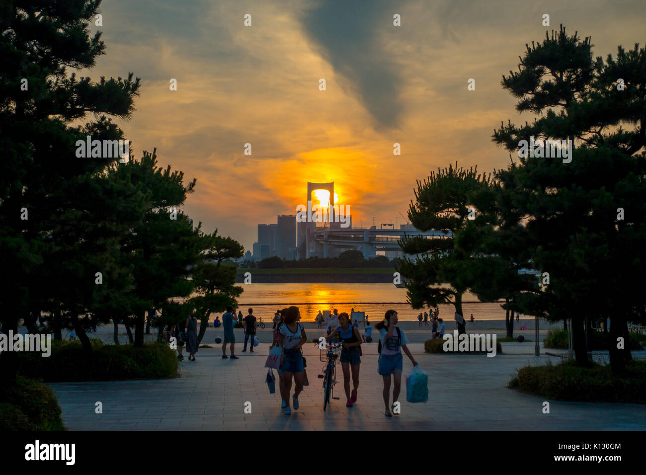 Tokio, Japan, 28. Juni - 2017: unbekannte Menschen zu Fuß in Odaiba Strand bei Sonnenuntergang, mit dem Osaiba Brücke im Horizont, Tokio, Japan Stockfoto