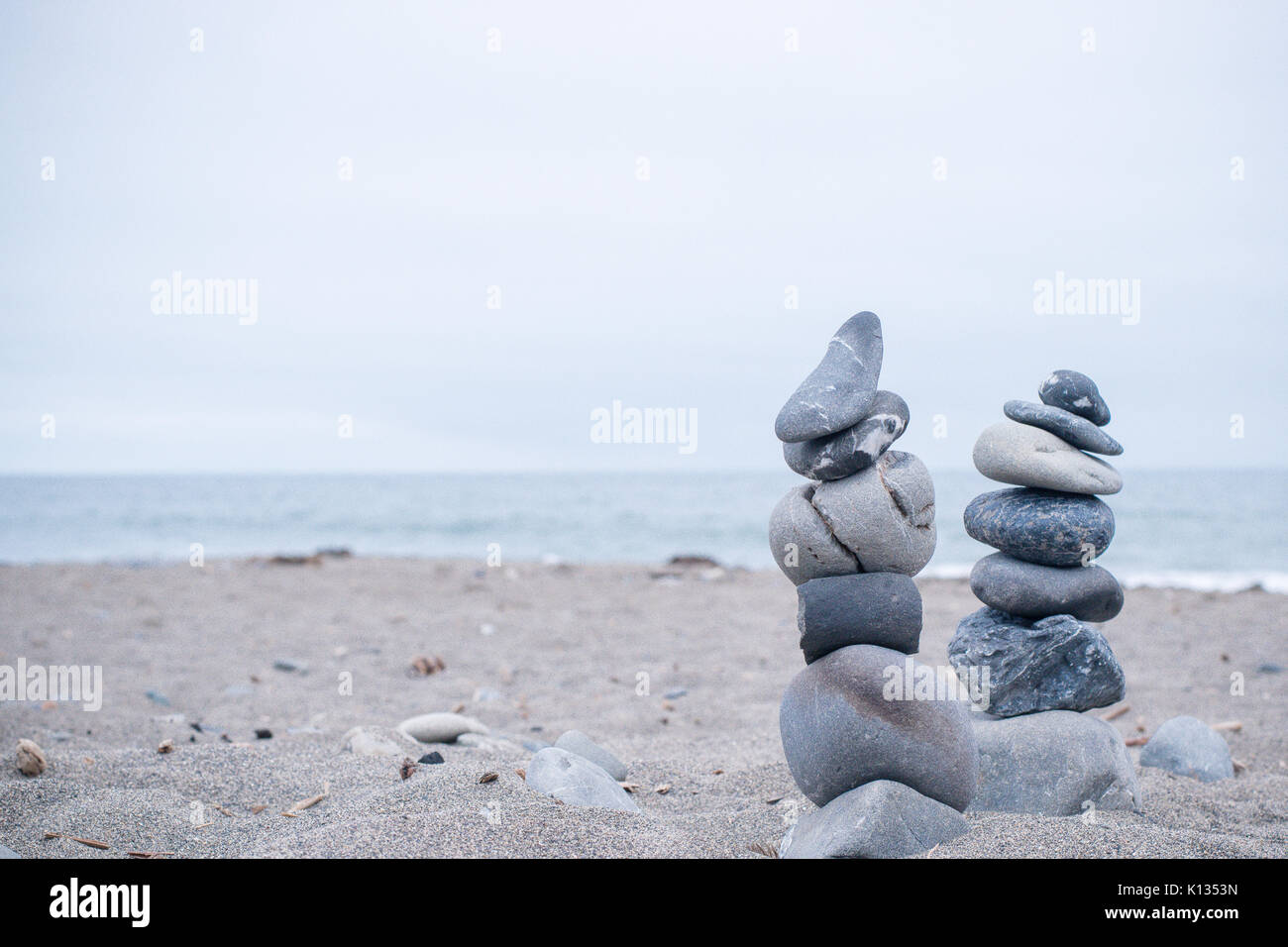 Monochrom, ruhigen, blauen gestapelte Steine auf einem Kalifornischen Strand als Symbol für Frieden, Gleichgewicht, Meditation und Achtsamkeit Stockfoto