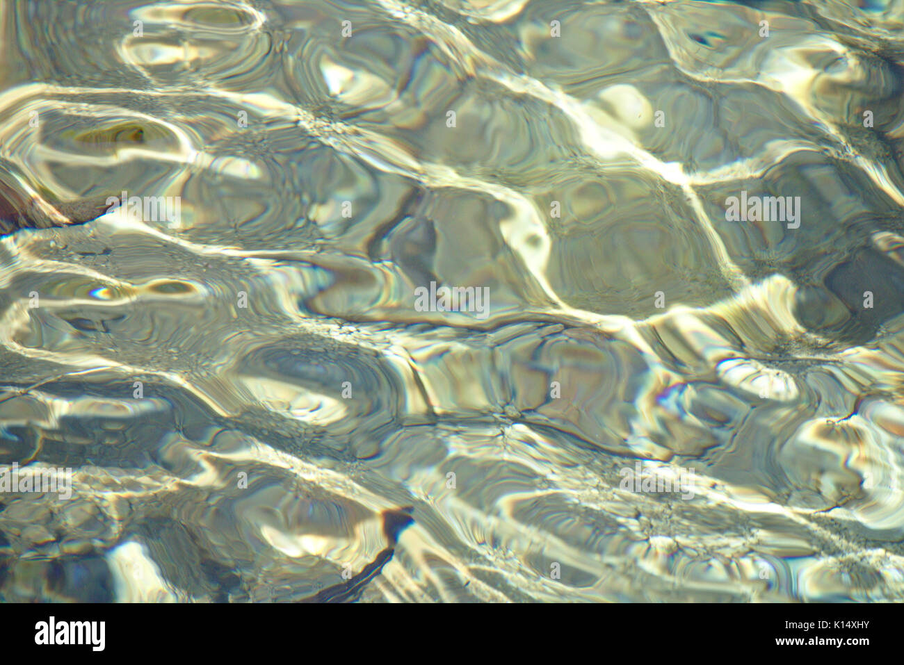 Flachwasser über Kies unten mit Reflexionen und kleinen plätschernden Wellen Stockfoto