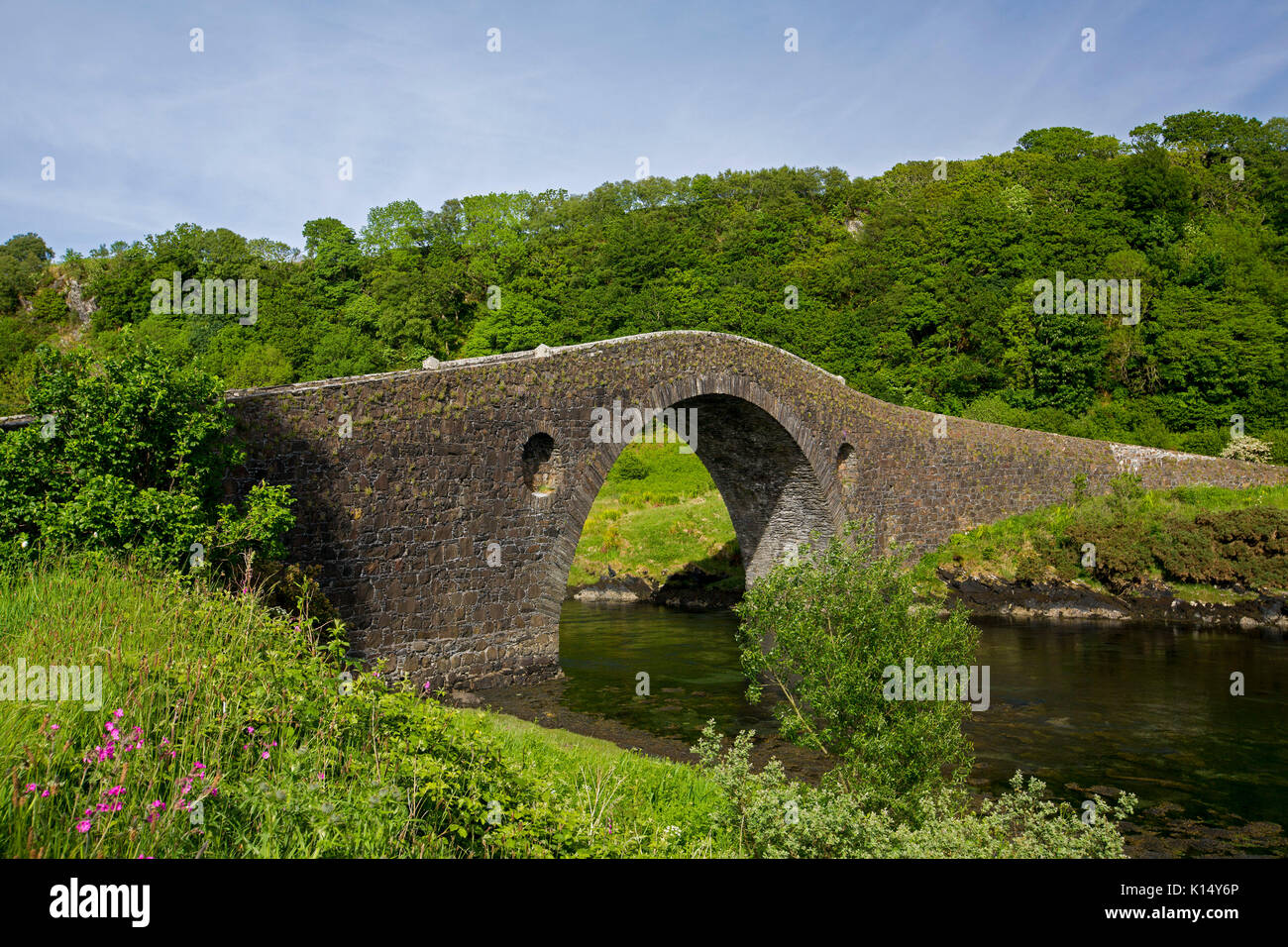 Historische gewölbten Stein Clachan Brücke über den schmalen Einlass des Atlantik gesäumt von smaragdgrünen Wälder, die Verknüpfung von Isle of Seil zu Festland Schottland Stockfoto