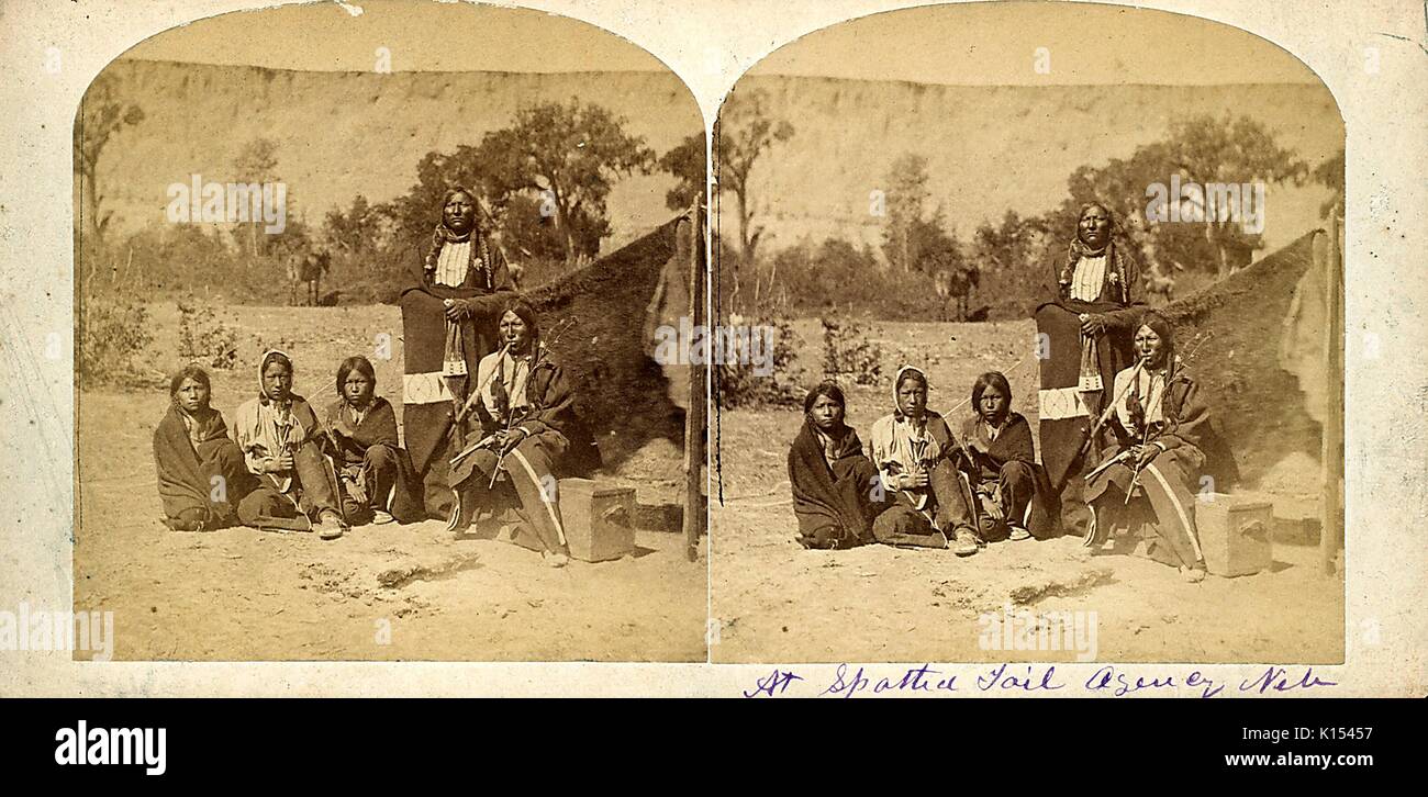 Stereographische Karte zeigt eine Gruppe von Sioux Personen, drei Frauen sitzen auf dem Boden, ein Mann saß auf einem Feld das Rauchen einer Pfeife, und ein Mann stand, handschriftliche unten im Bild wird in Spotted Tail Agentur, Nebraska, 1865. Stockfoto