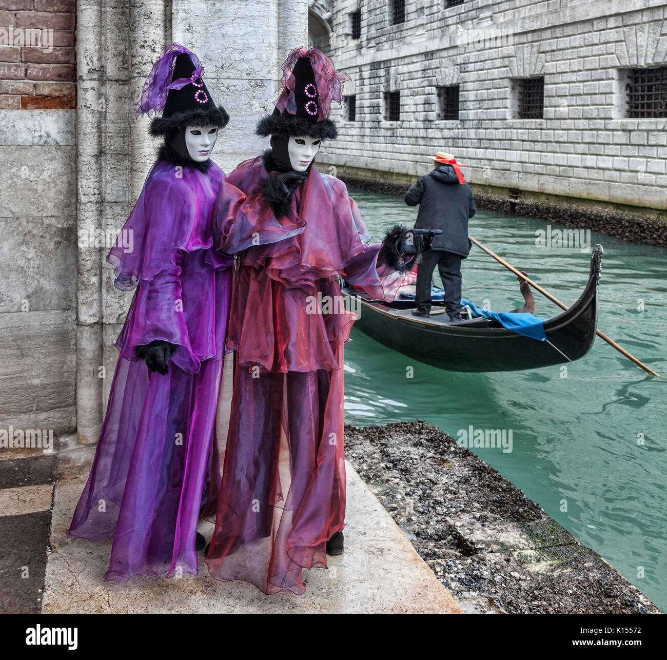 Venedig, Italien - 18 Februar 2012: Zwei Personen tragen bestimmte Kostüme und Masken, während ein gondoliere, vorbei an einem kleinen Kanal in Venedig während ist Stockfoto