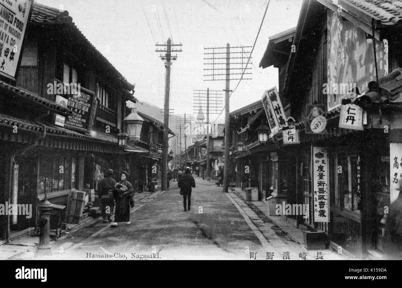 Eingefärbte Postkarte von Hamano-Cho, mit Menschen auf einer Straße mit Geschäften, Nagasaki, Japan, 1912 gesäumt. Von der New York Public Library. Stockfoto