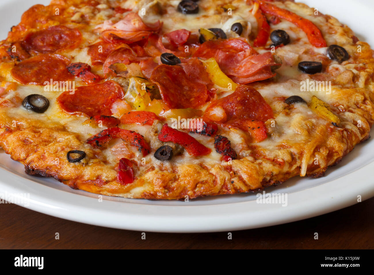 Top Supreme Pizza mit Salami, Wurst, Speck, Paprika, Zwiebel und schwarzen Oliven Stockfoto