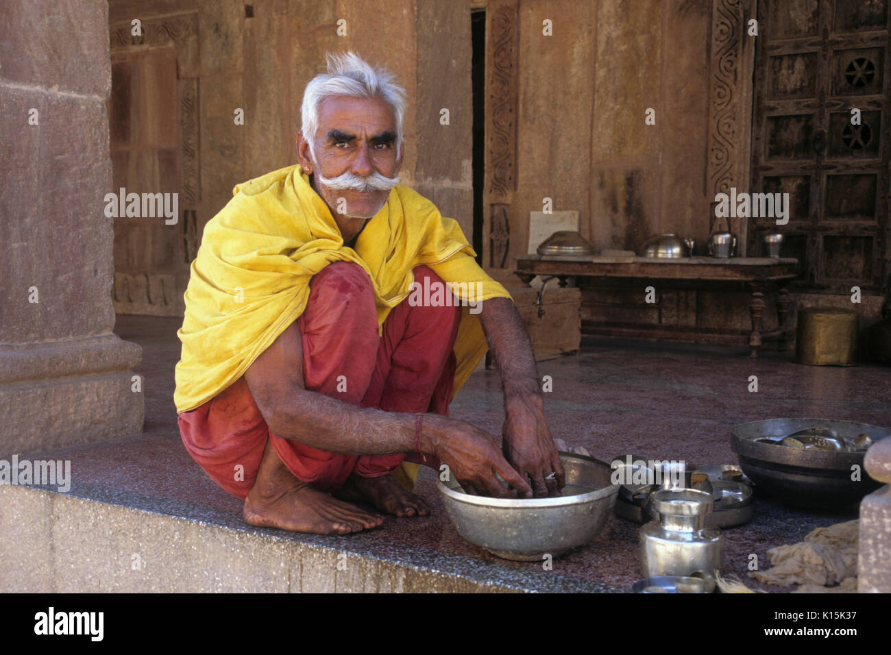 Mann, das Waschen von Töpfen zu einem Jain Tempel, Osian, Rajasthan, Indien Stockfoto