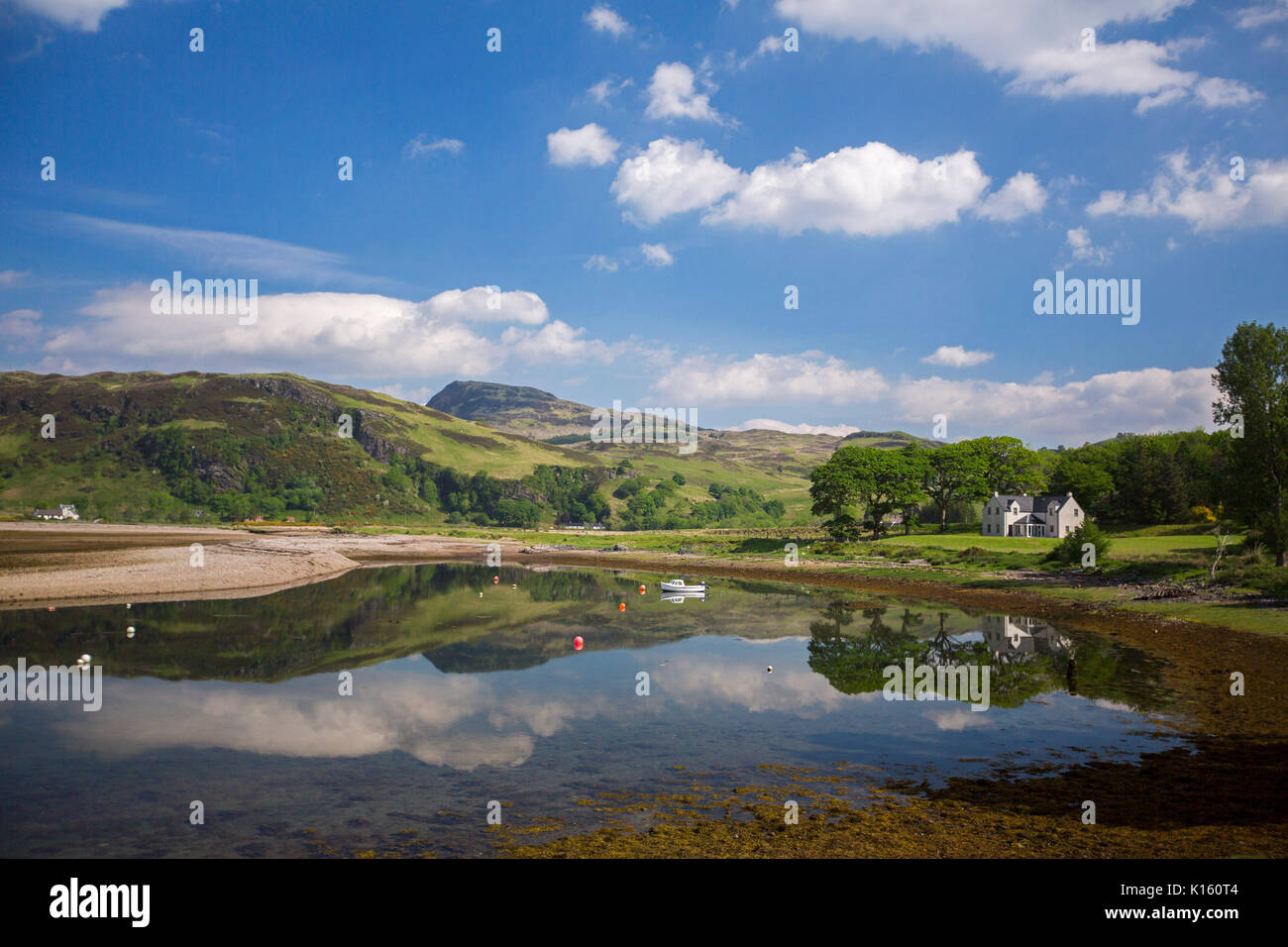 Atemberaubende Landschaft mit Bergen, blauer Himmel und weiße Haus in ruhigen Gewässern des Loch wider, & Sandstrand mit Bäumen in der Nähe von Glenelg Schottland gesäumt Stockfoto