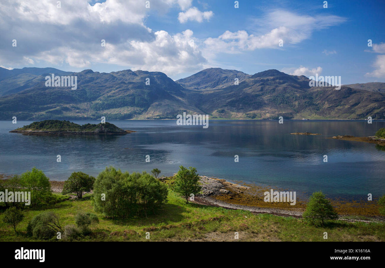 Eine atemberaubende Landschaft mit weiten, blauen Wasser von Glenelg Bucht und bewaldete Insel von Bergen unter blauem Himmel in Schottland umhüllt Stockfoto