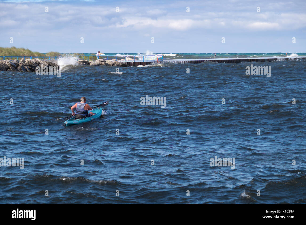 Kayaker paddeln durch den Weißen See Kanal in den Lake Michigan gegenüber gefährlichen Wasser. Stockfoto