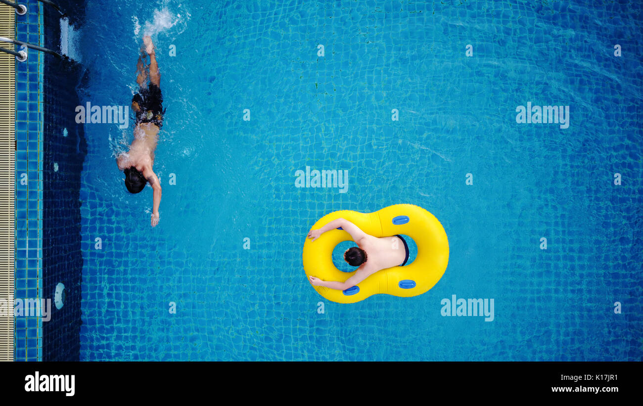 Ansicht von oben, ein Mann entspannt auf gelb Pool schwimmen, am Pool im Sommer Stockfoto