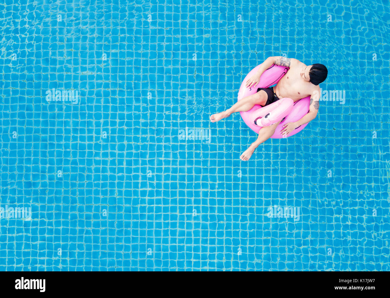 Ansicht von oben, ein Mann entspannt auf rosa Pool schwimmen, am Pool im Sommer Stockfoto