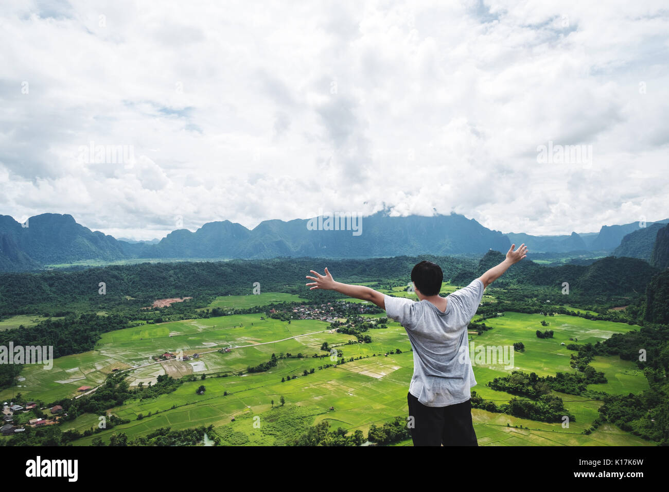 Ein Mann die Hand heben auf der Bergspitze, in tropischen Landschaft reisen, Vang Vieng in Laos. Stockfoto