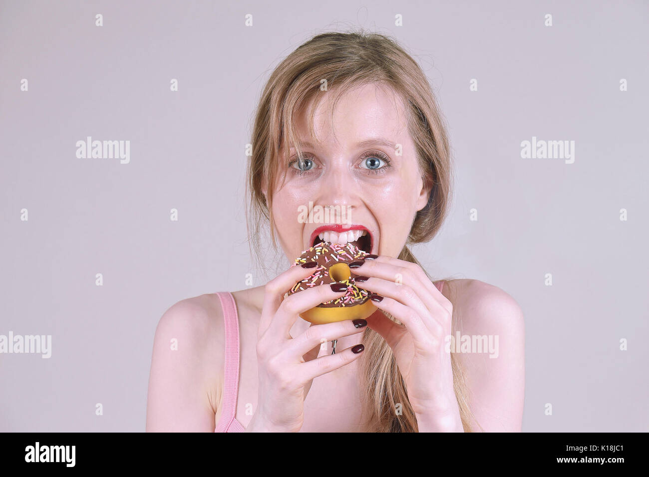 Junge Frau Schokolade essen Donut mit offenen Mund Stockfoto