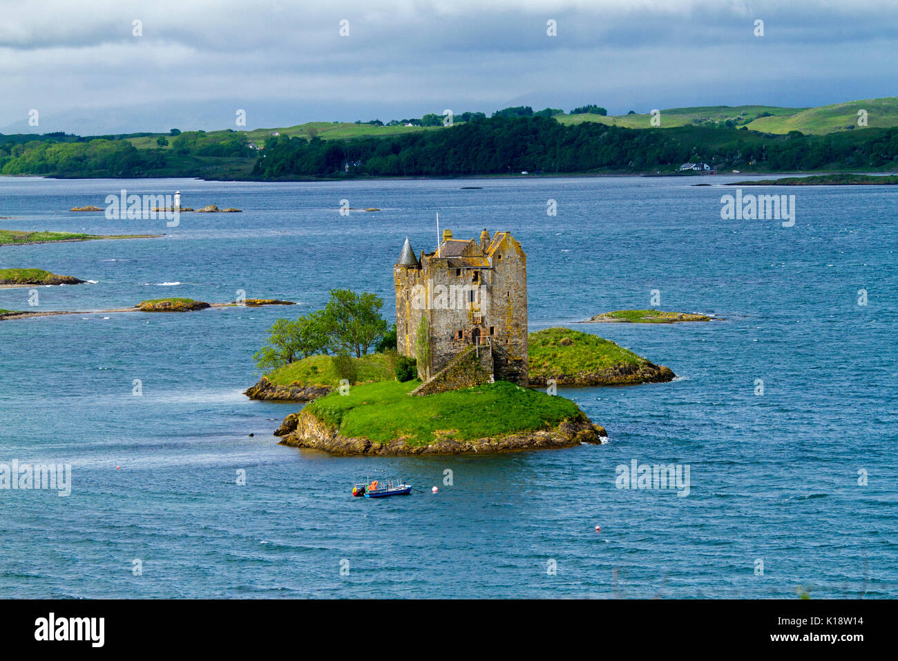 Castle Stalker, das Tower House/auf der winzigen Insel im Loch Laich, in der Nähe von Port Appin, Argyll, Schottland, mit einem kleinen Boot und einem kleinen Leuchtturm in der Nähe Stockfoto