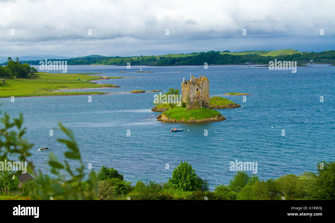 Castle Stalker, das Tower House/auf der winzigen Insel im Loch Laich, in der Nähe von Port Appin, Argyll, Schottland, mit einem kleinen Boot und einem kleinen Leuchtturm in der Nähe Stockfoto