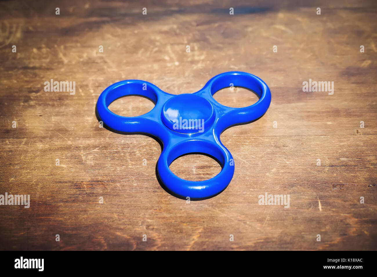 Blau zappeln Spinner auf Holztisch isoliert. Leistungsstarke Spinner, Spinner, Twister für Hände Unterhaltung rotierende Spielzeug Stockfoto