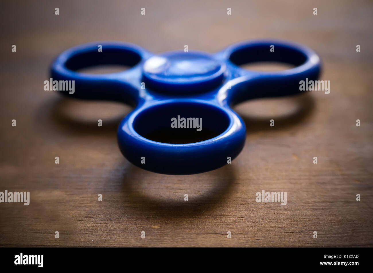 Blau zappeln Spinner auf Holztisch isoliert. Leistungsstarke Spinner, Spinner, Twister für Hände Unterhaltung rotierende Spielzeug Stockfoto