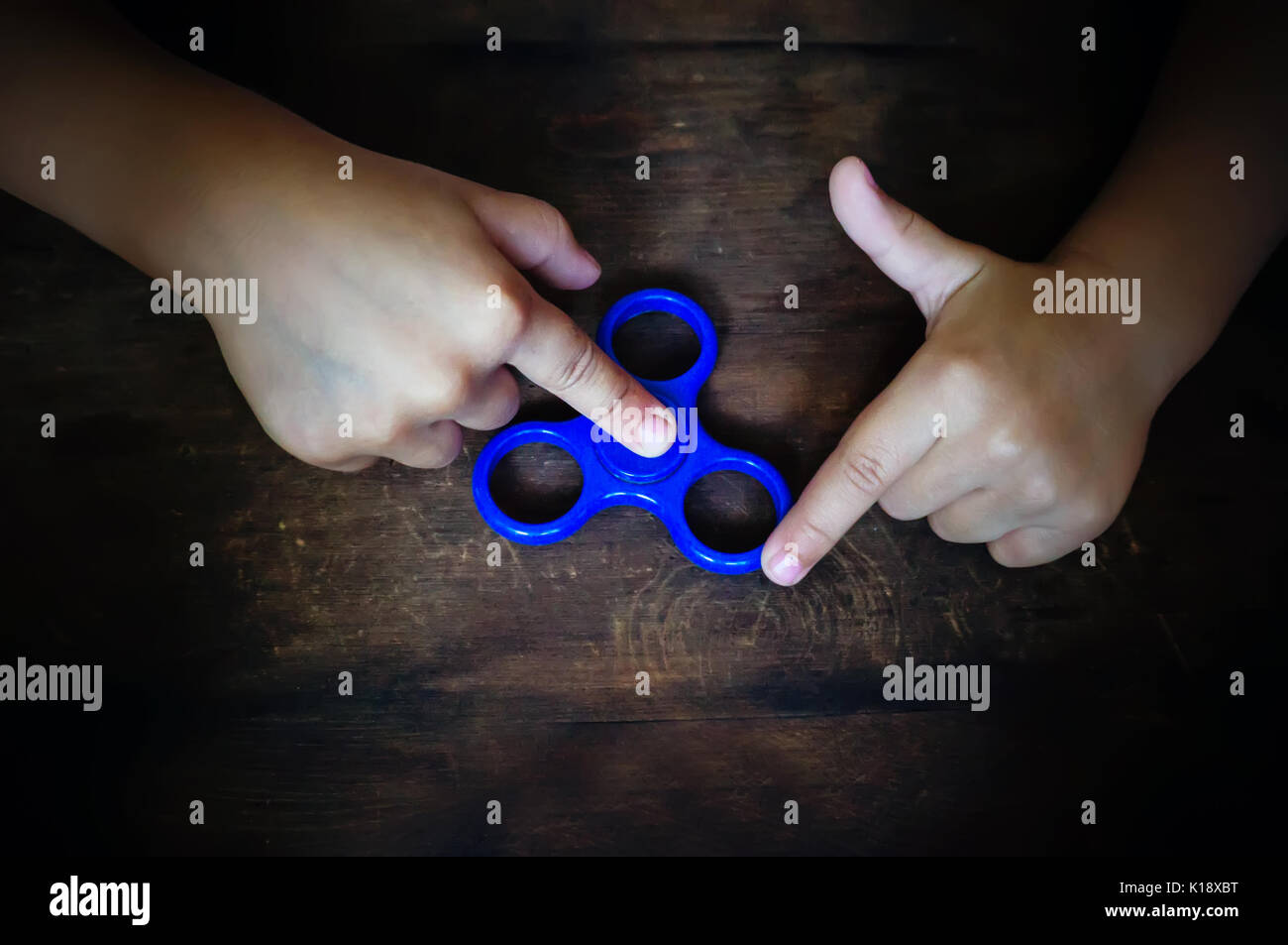 Leistungsstarke Spinner, Twister für Hände Unterhaltung rotierende Spielzeug. die Hände des Kindes Spinner auf einem Holztisch twist Stockfoto