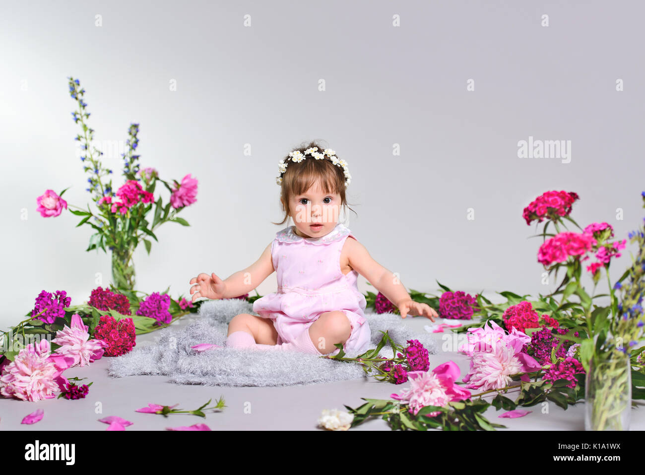 Schönes baby sitzend mit einem Blumenstrauß Stockfoto