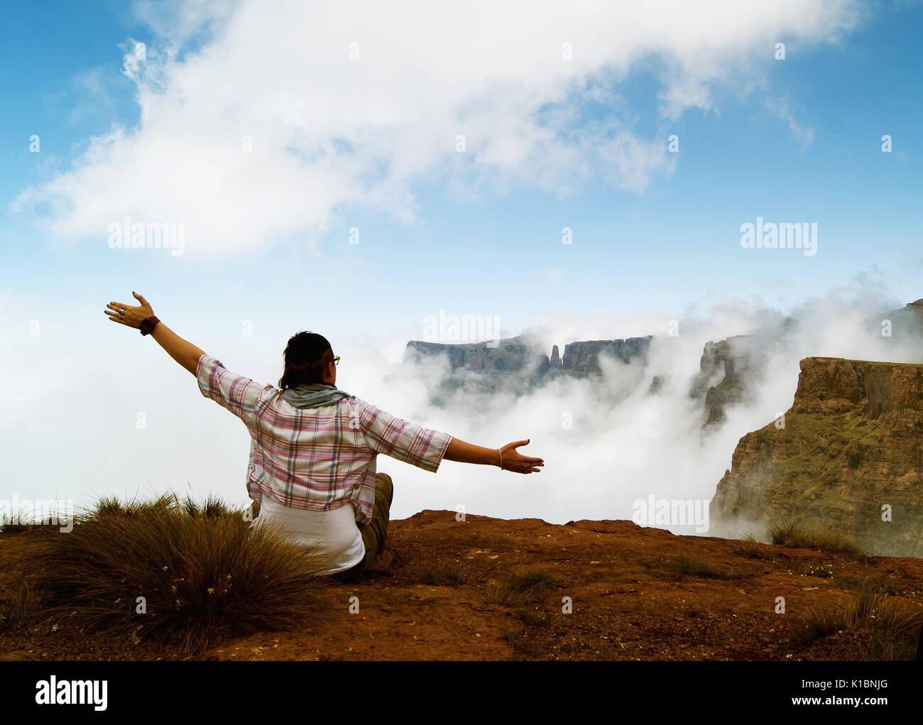 Das Mädchen sitzt auf einem Berg oberhalb der Wolken, Wasserfall Tugela Stockfoto