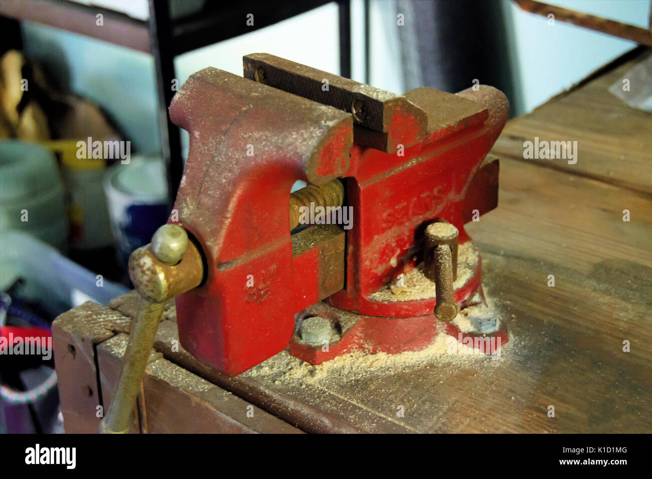 Eine rote rustikalen Schraubstock sitzen auf einer Werkbank mit Holz Staub bedeckt. Stockfoto