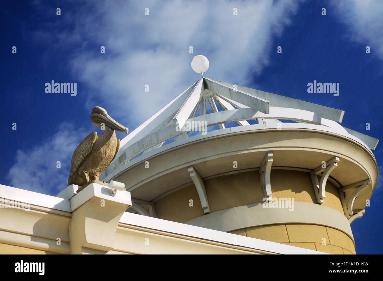 Ein Stein pelican Statue auf Stuck neben einer Kuppel in einem Winkel am Pelican Plaza in Gulf Shores Florida sitzt. Stockfoto