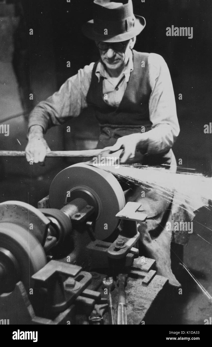 Ein Mitarbeiter des Bureau of Entomology and Plant Quarantine schärft die Achsen mit einer Schleifscheibe, Bloomfield, New Jersey, 1938. Aus der New York Public Library. Stockfoto