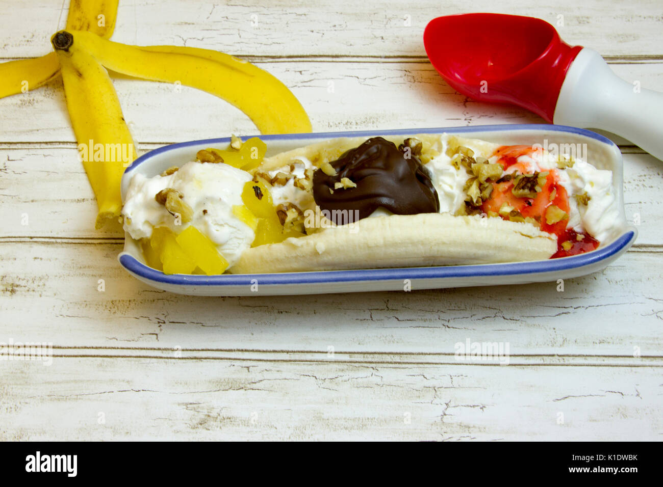 Banana Split mit Schale und Eisportionierer in Boot auf rustikalen, mit Holz. Stockfoto