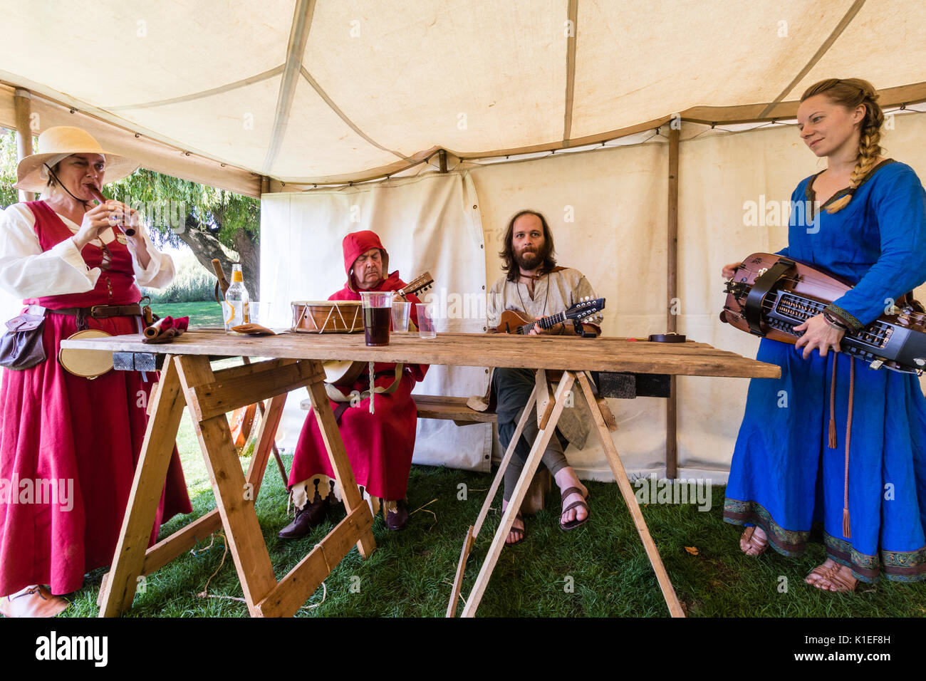 England, Sandwich. Mittelalterliche band der Spielleute spielen verschiedene Arten von mittelalterlichen Musikinstrumente um hölzernen Tisch in einem Zelt. Stockfoto