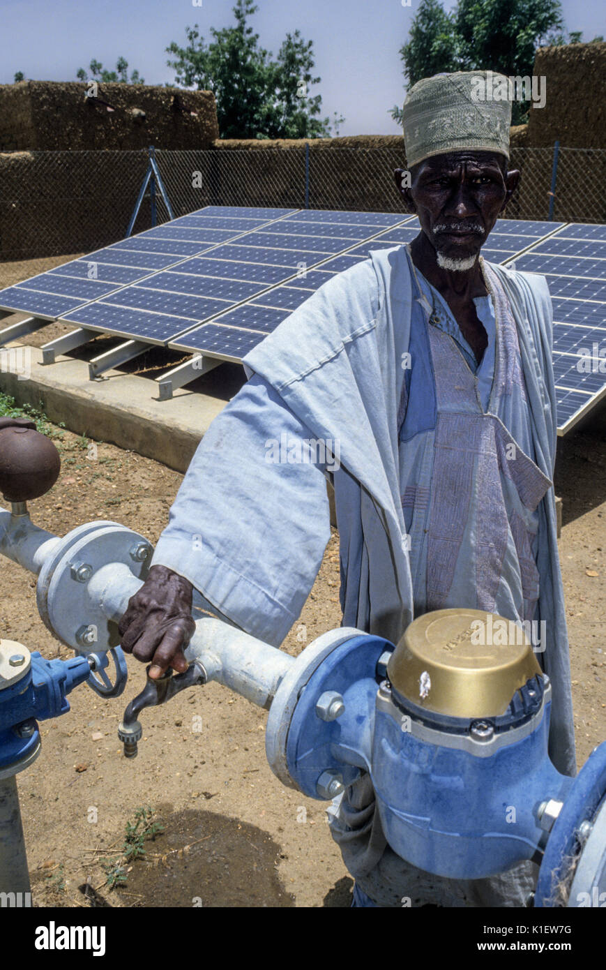 Niger, Kantche, West Afrika. Ein Dorfältester, mit Solarzellen im Hintergrund für die Stromversorgung Dorf Wasserpumpe. Stockfoto