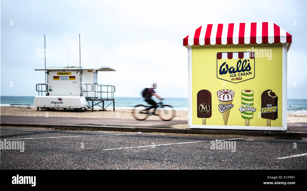 BOURNMOUTH, UK - 22. AUGUST 2017: Radfahrer, reitet ein Rettungsschwimmer Station auf dem Weg zu einer Wände Eis am Strand von Bournemouth stehen Stockfoto